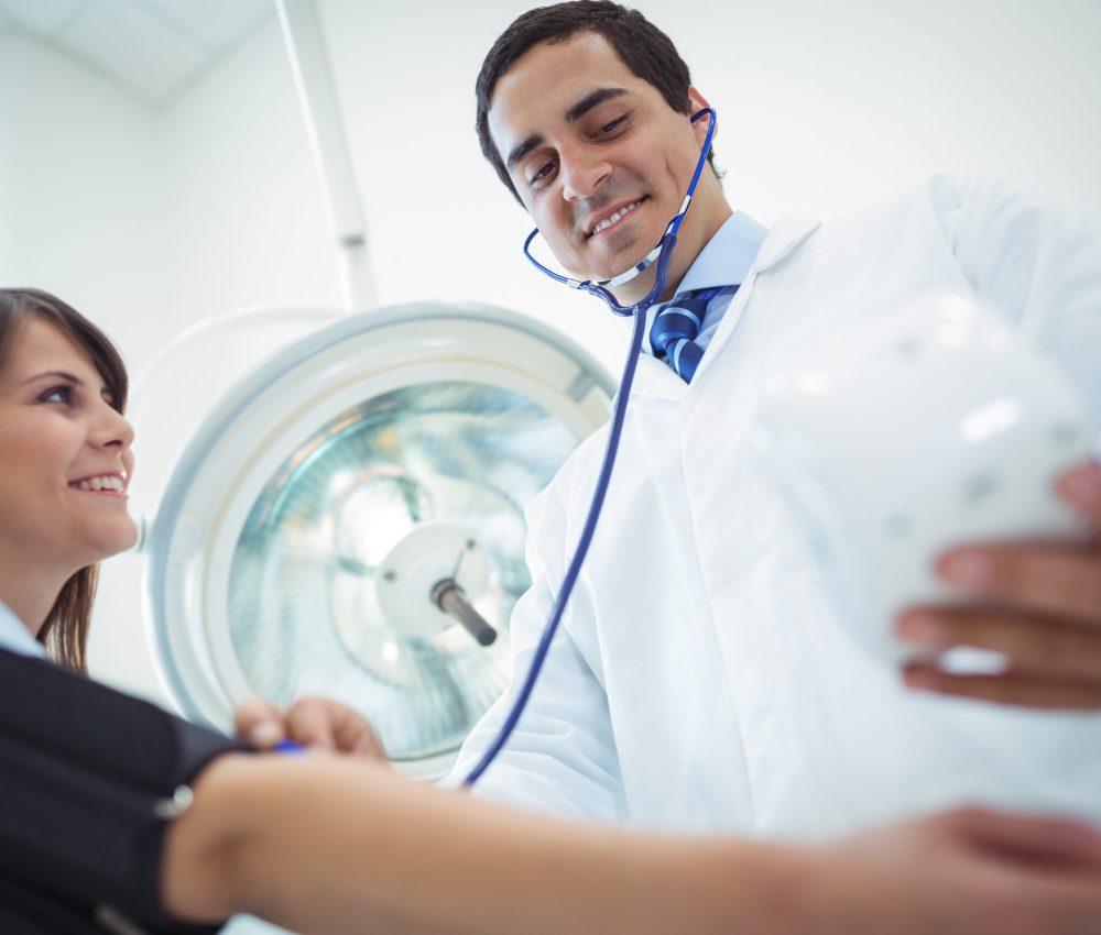 Doctor checking female patient blood pressure in the hospital